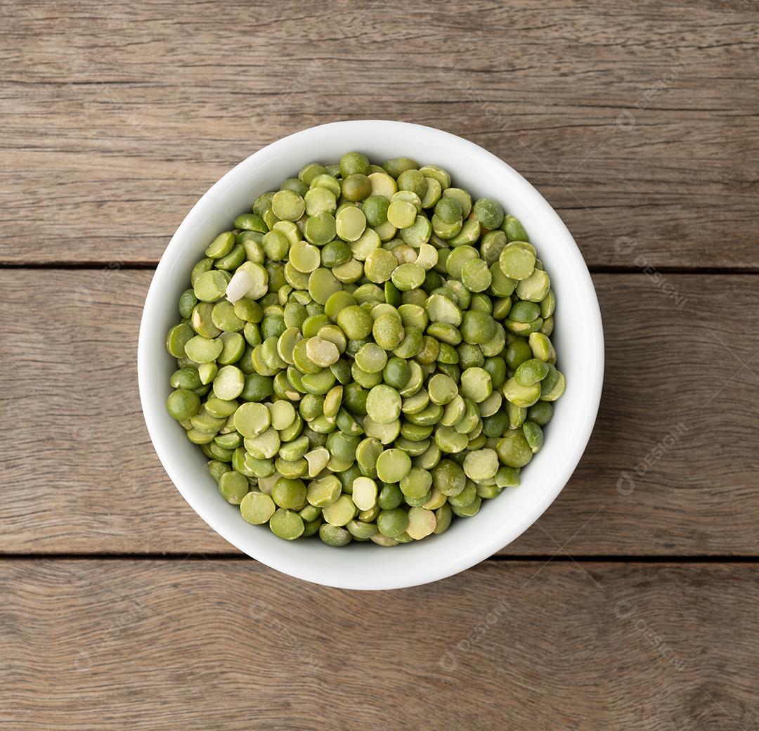 Ervilhas verdes secas cruas em uma tigela sobre mesa de madeira