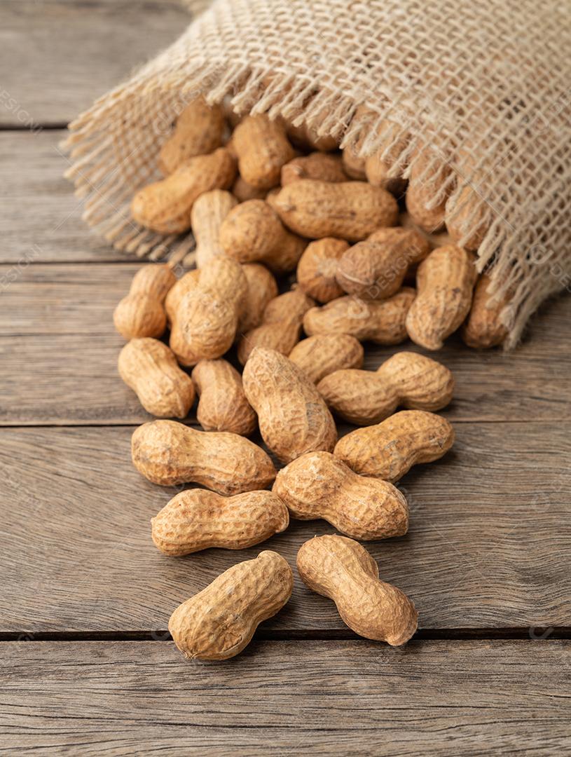 Uma pilha de amendoins em um saco sobre mesa de madeira