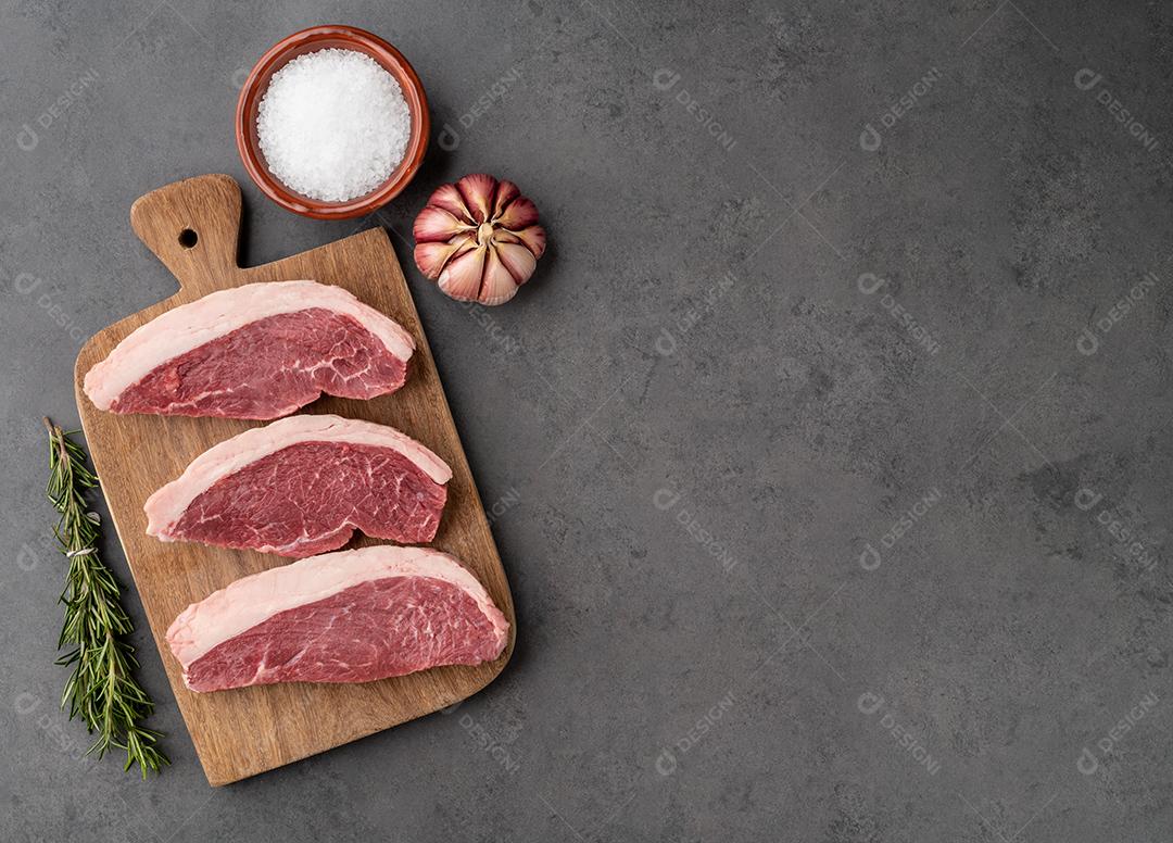 Picanha crua fatiada ou carne de alcatra sobre tábua de madeira com tempero