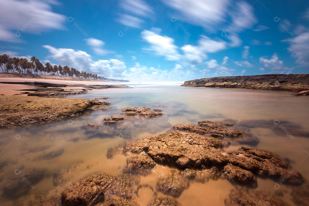 Paisagem de praia tropical com coqueiros e rochas longas exposições