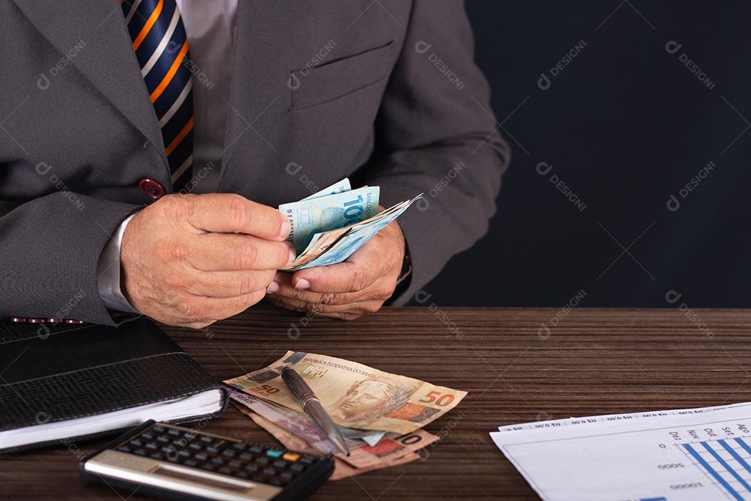 Empresário trabalhando em seu escritório e contando dinheiro em dinheiro