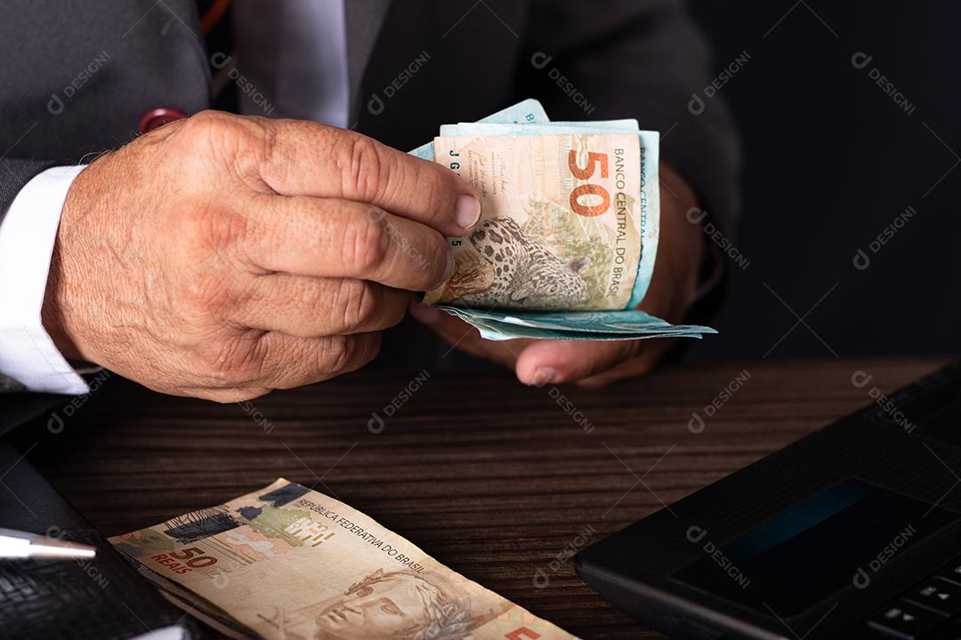 Empresário trabalhando em seu escritório e contando dinheiro em dinheiro