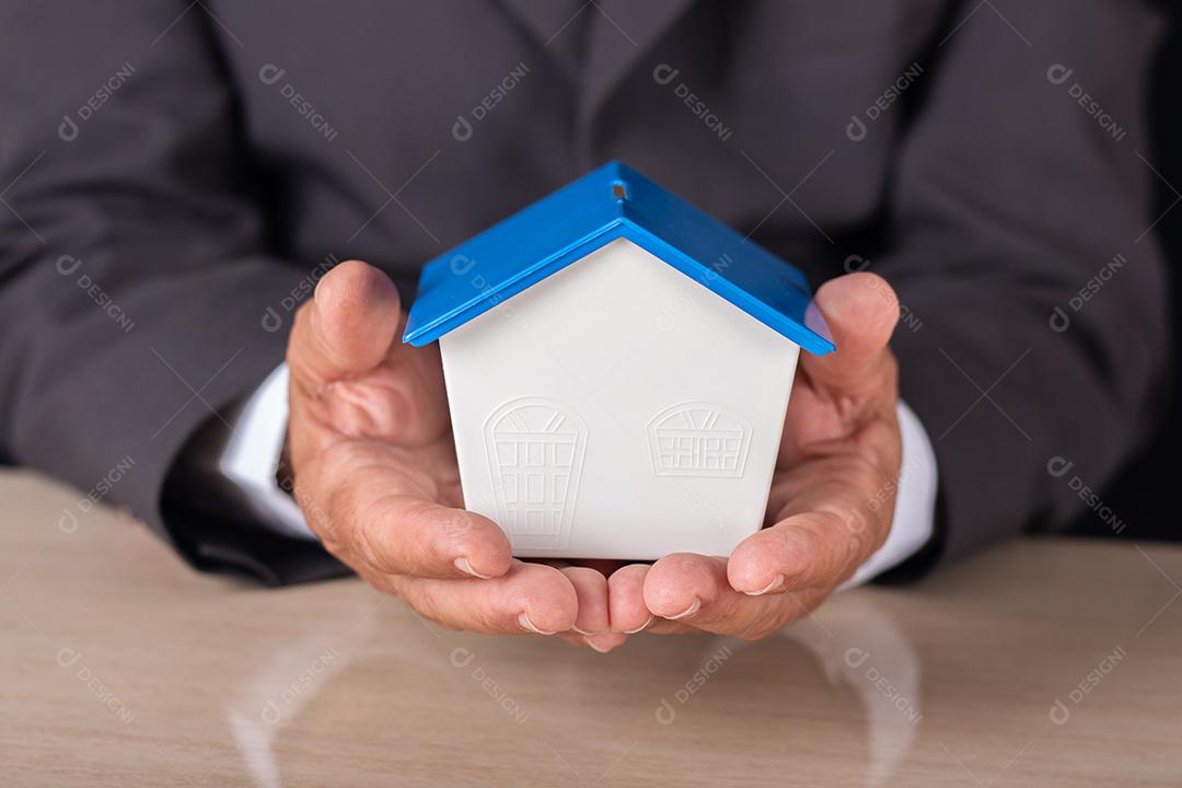 Business man holding a small house in his hand. housing concept
