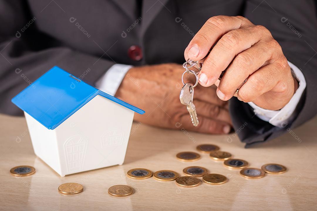 Homem de negócios segurando chave com casa pequena na mesa. habitação