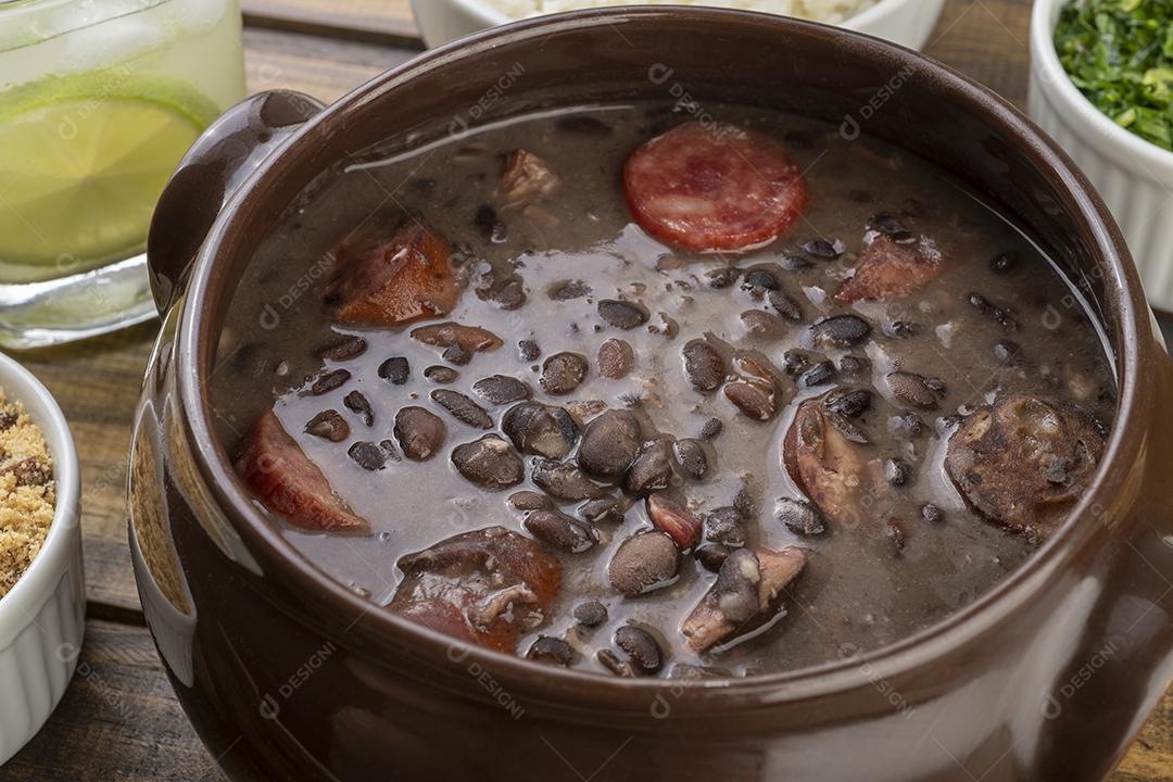 Tradicional feijoada brasileira com couve, farinha de mandioca e caipi
