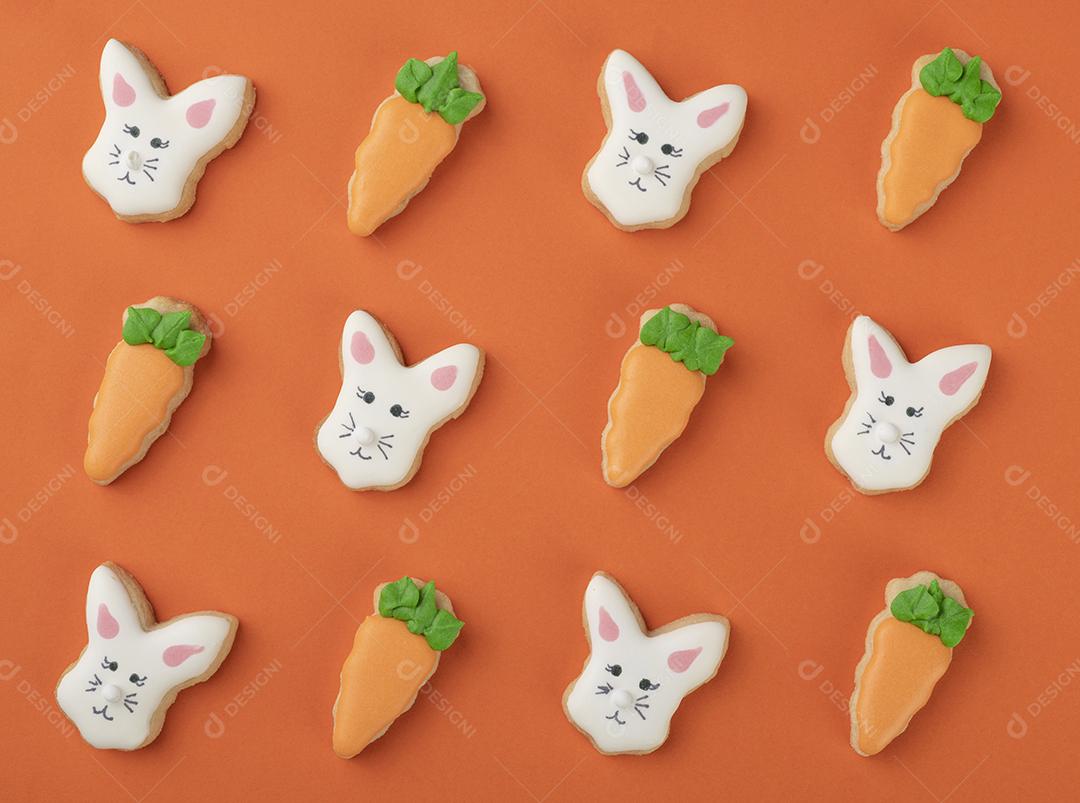Biscoitos de coelhinho e cenoura de páscoa sobre fundo laranja