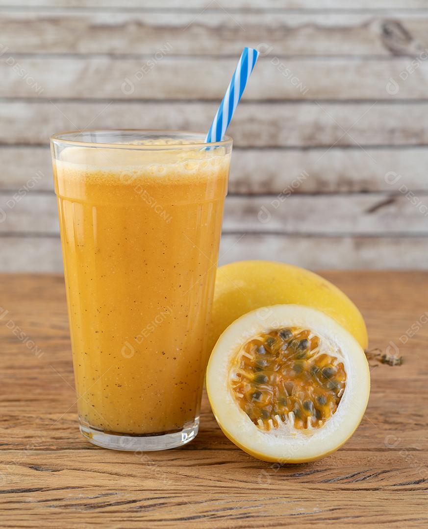 Suco de maracujá em um copo com frutas sobre mesa de madeira