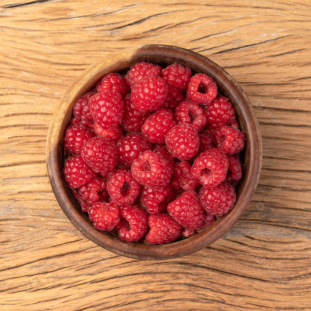 Framboesas em uma tigela sobre mesa de madeira