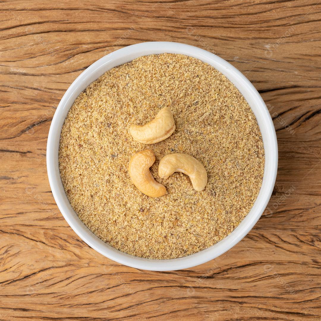 Farinha de castanha de caju em uma tigela sobre mesa de madeira. Farinha sem glúten