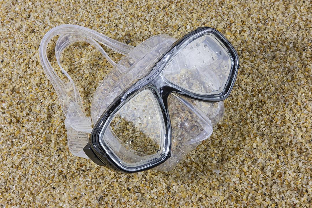 Máscara de mergulho molhada sobre uma areia da praia. Esportes de verão e lazer
