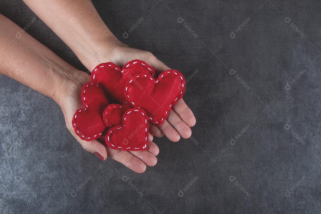 Fundo do Dia dos Namorados com a mão segurando corações vermelhos.