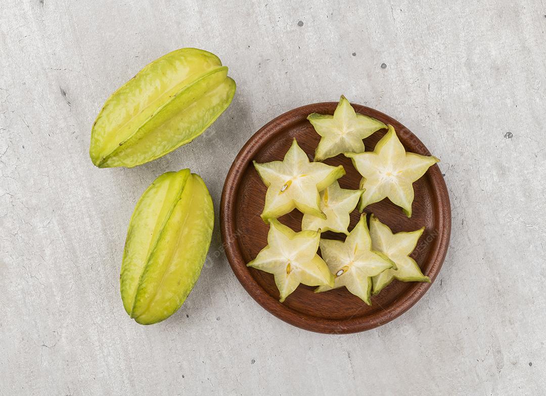 Frutas estelares com fatias sobre um prato de madeira