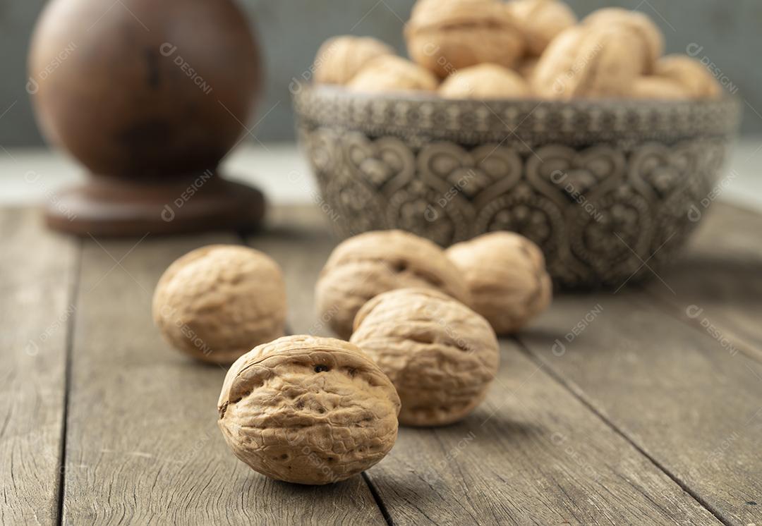 Nozes sobre uma mesa de madeira e em uma tigela