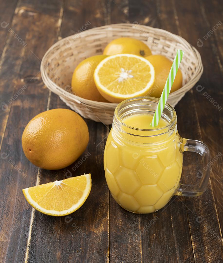 Suco de laranja com laranjas em uma cesta e cortar frutas sobre madeira