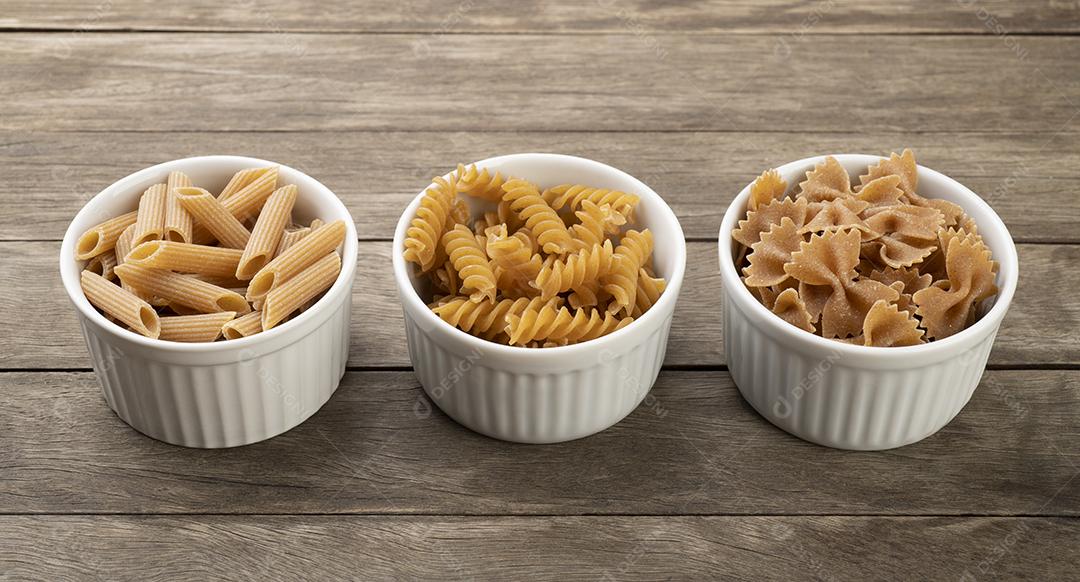 Massa de trigo integral variada em tigelas sobre mesa de madeira