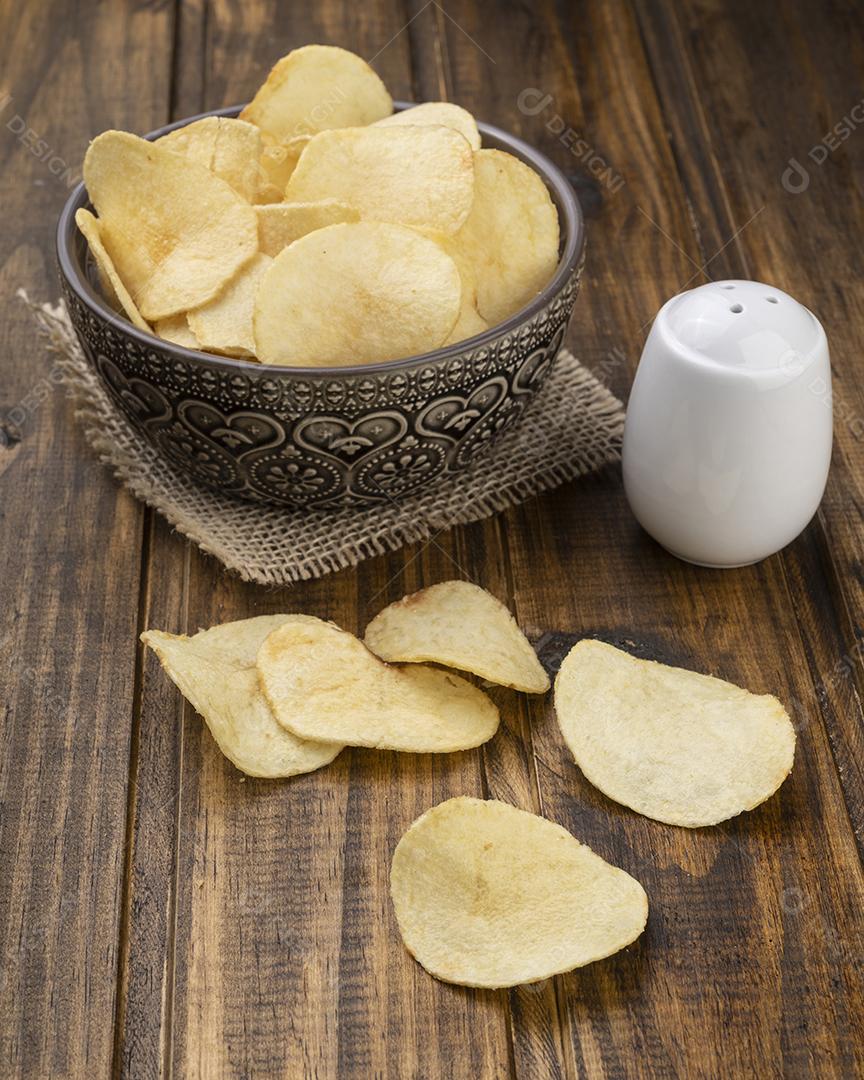 Batatas fritas em uma tigela com sal sobre mesa de madeira