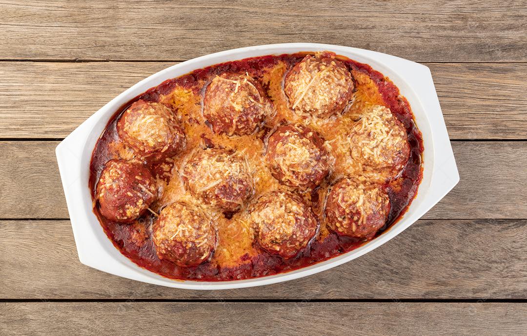 Bolas de carne em um prato branco com molho de tomate e queijo derretido.