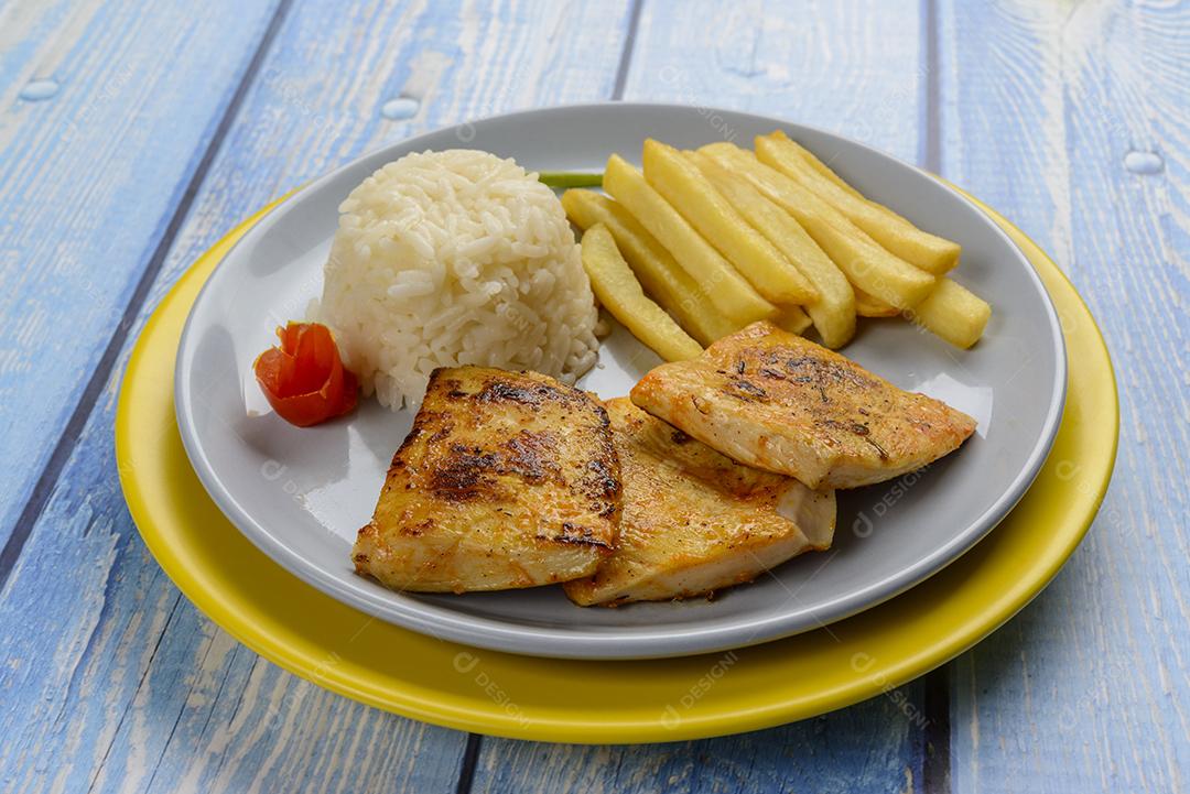 Peito de frango frito, menu infantil de restaurante, com arroz branco e batata frita.