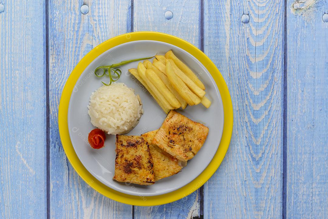 Peito de frango frito, menu infantil de restaurante, com arroz branco e batata frita.