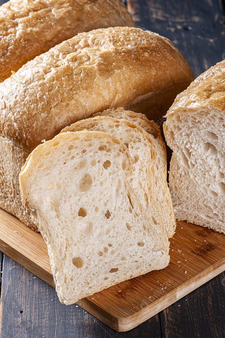 Pão de fermentação natural fatiado em tábua de madeira.