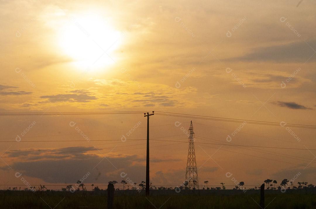 Céu com nuvens claras e por do sol, em campo. Paisagem