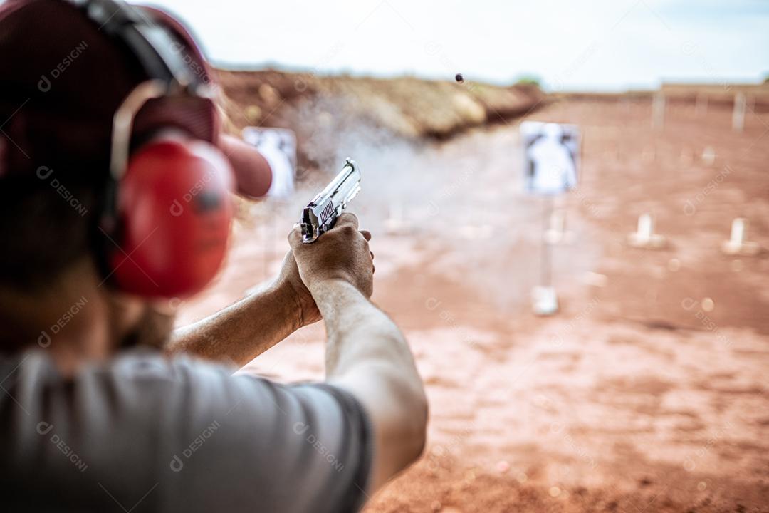 Visão detalhada atirador segurando arma treinando tiro tático, foco na pistola. Campo de tiro