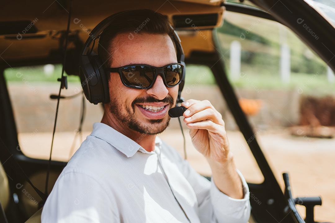 Piloto com fone de ouvido iniciando controles em helicóptero privado