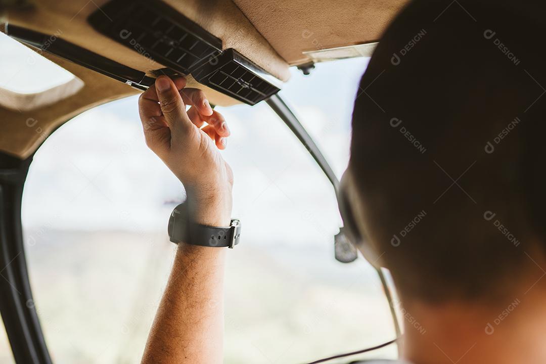 Piloto com fone de ouvido iniciando controles em helicóptero privado