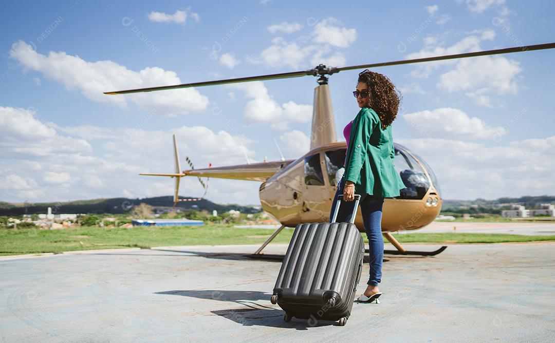 Bem sucedida inteligente elegante jovem Latina perto de helicóptero. Luxo