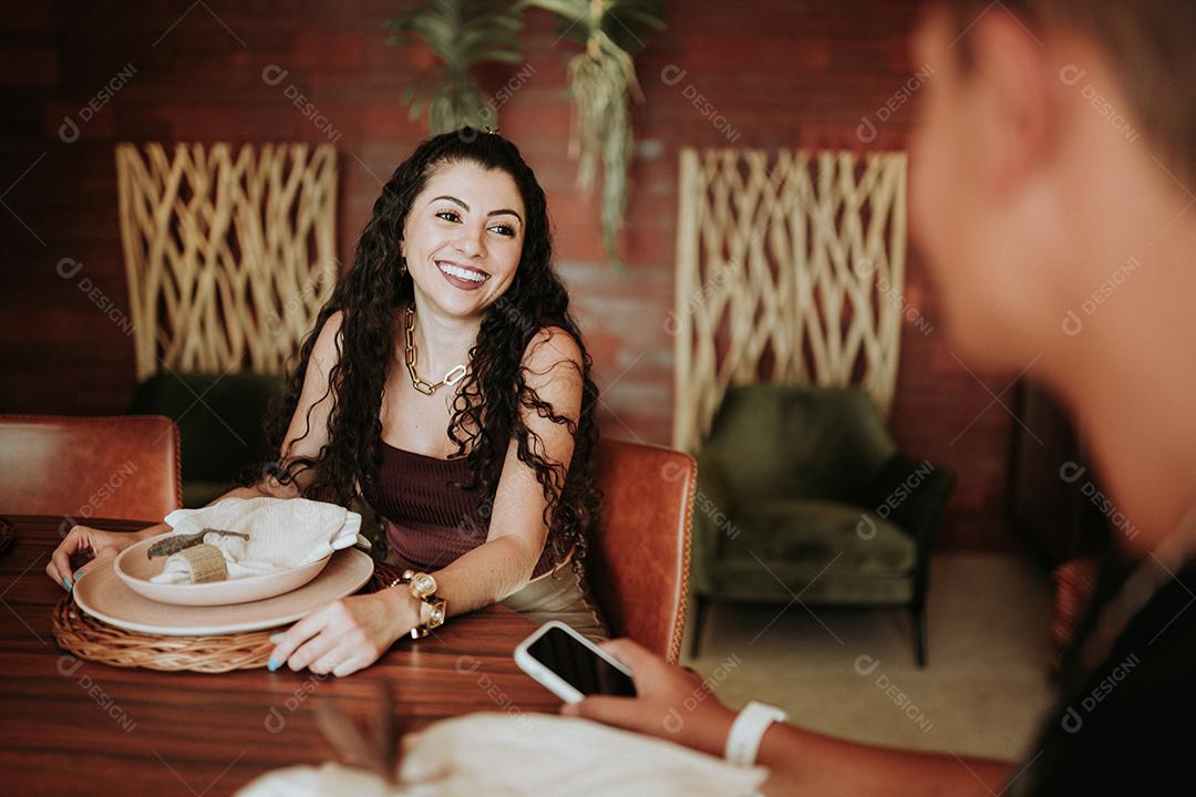 Dois amigos latinos reunidos em volta de uma mesa em um restaurante