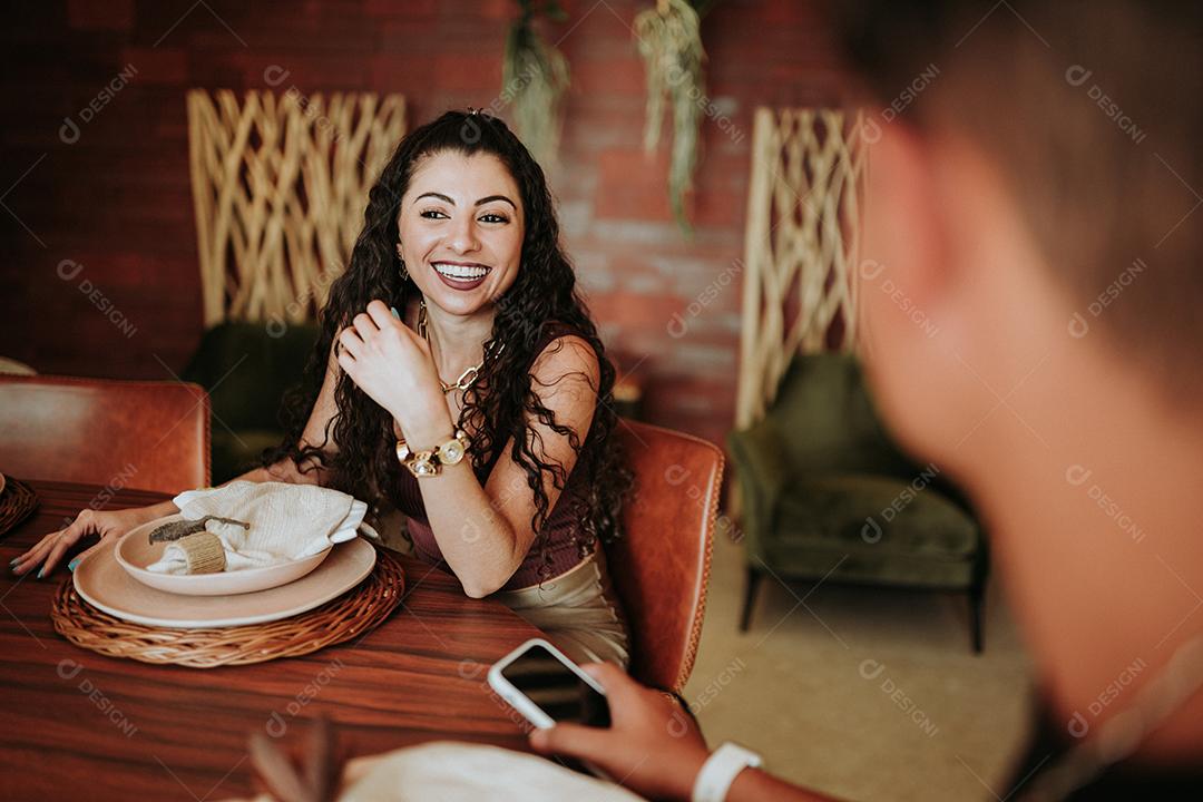 Dois amigos latinos reunidos em volta de uma mesa em um restaurante