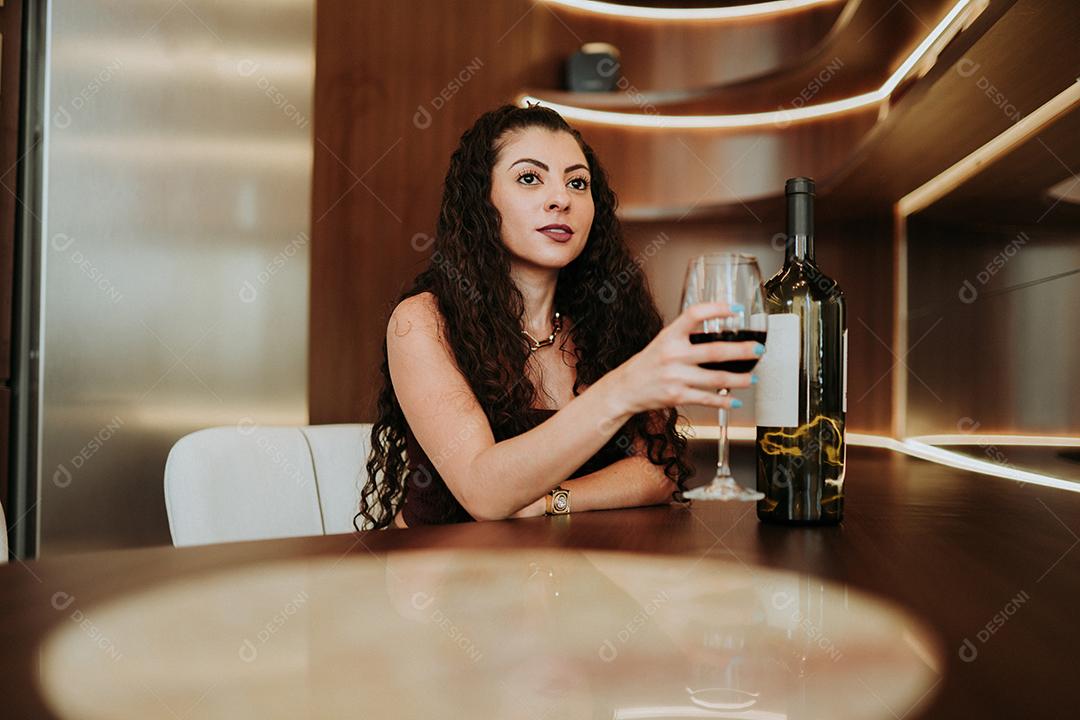 Uma jovem linda mulher latina na mesa segurando um copo