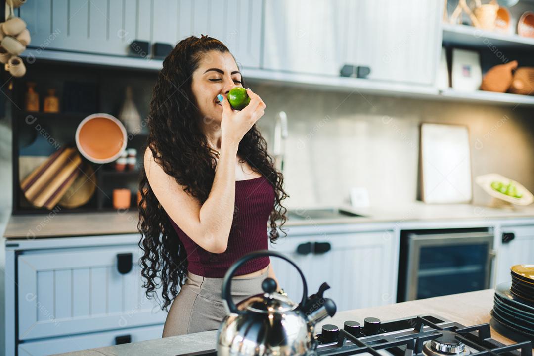 Jovem mulher latina em casa preparando chá na cozinha.