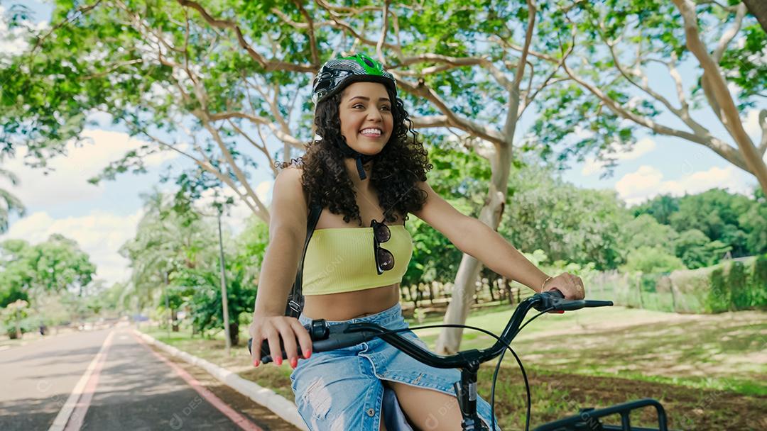 Jovem mulher latina em capacete protetor está andando de bicicleta