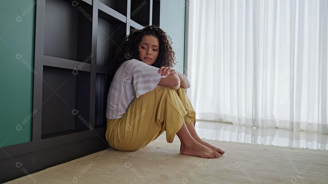 Mulher latina sentada no chão se sente infeliz por problemas pessoais