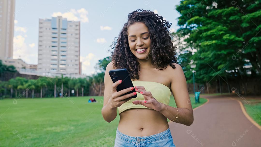 Mulher latina usando smartphone no parque. menina brasileira.