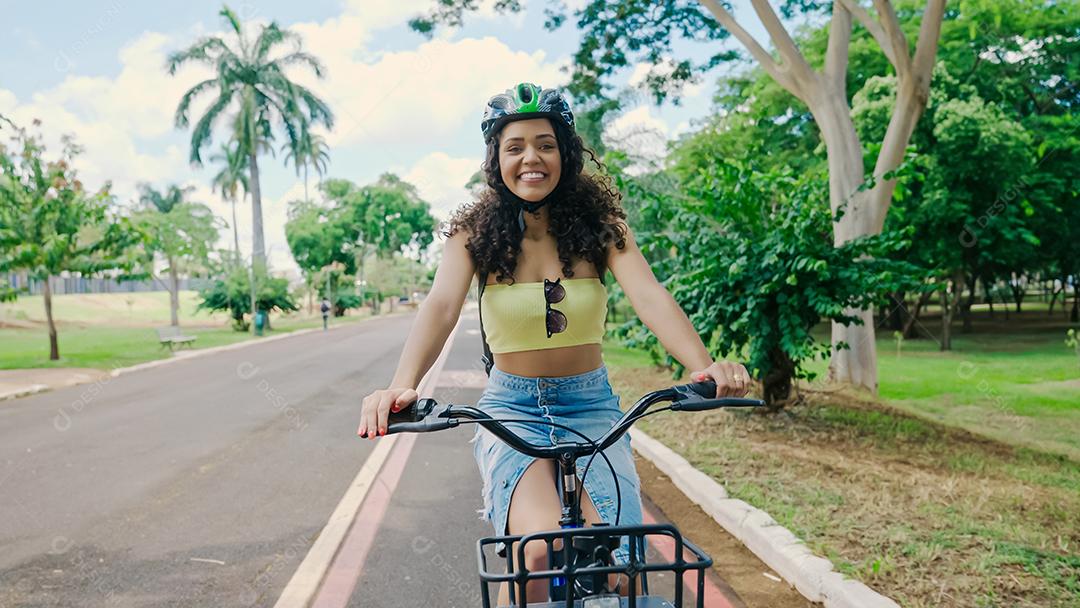Jovem mulher latina em capacete protetor está andando de bicicleta