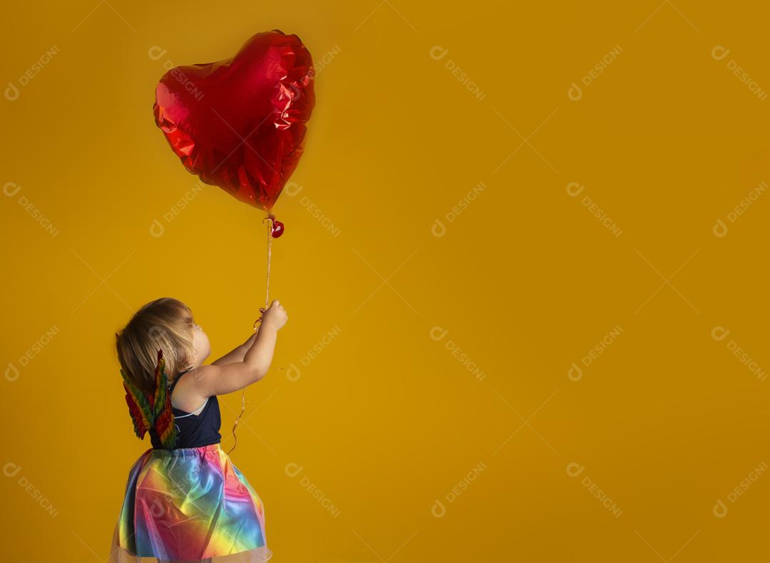 Cupido bonito com balão de forma de coração vermelho sobre fundo amarelo