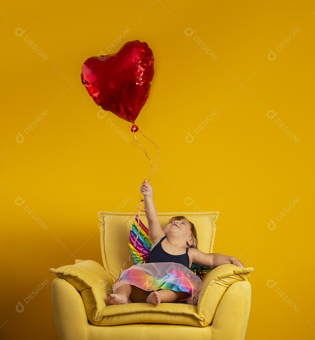 Cupido bonito com balão de forma de coração vermelho sobre fundo amarelo