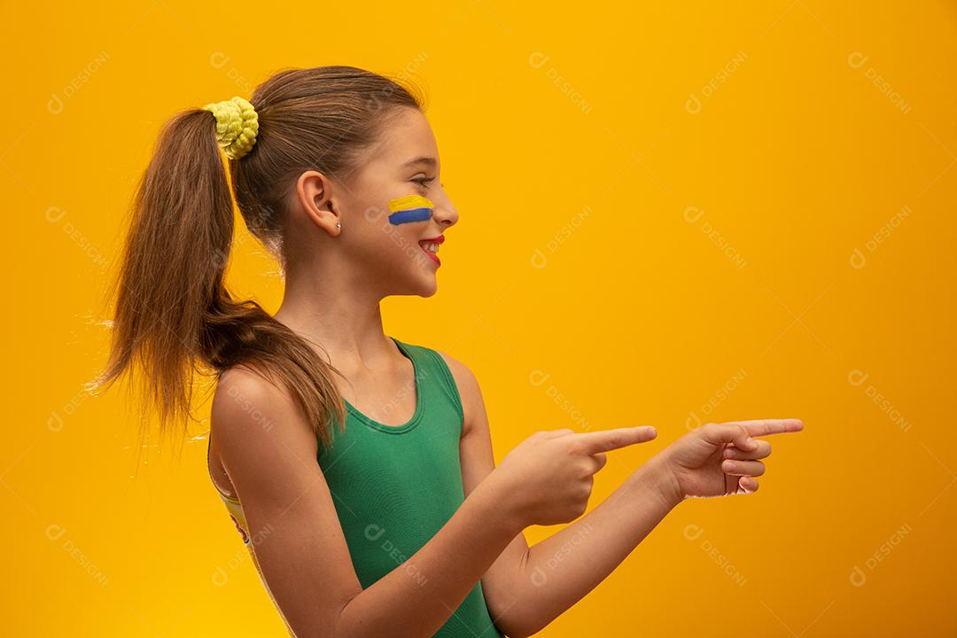 Torcedor de futebol, seleção brasileira. Copa do Mundo. Linda garotinha torcendo por seu time em fundo amarelo