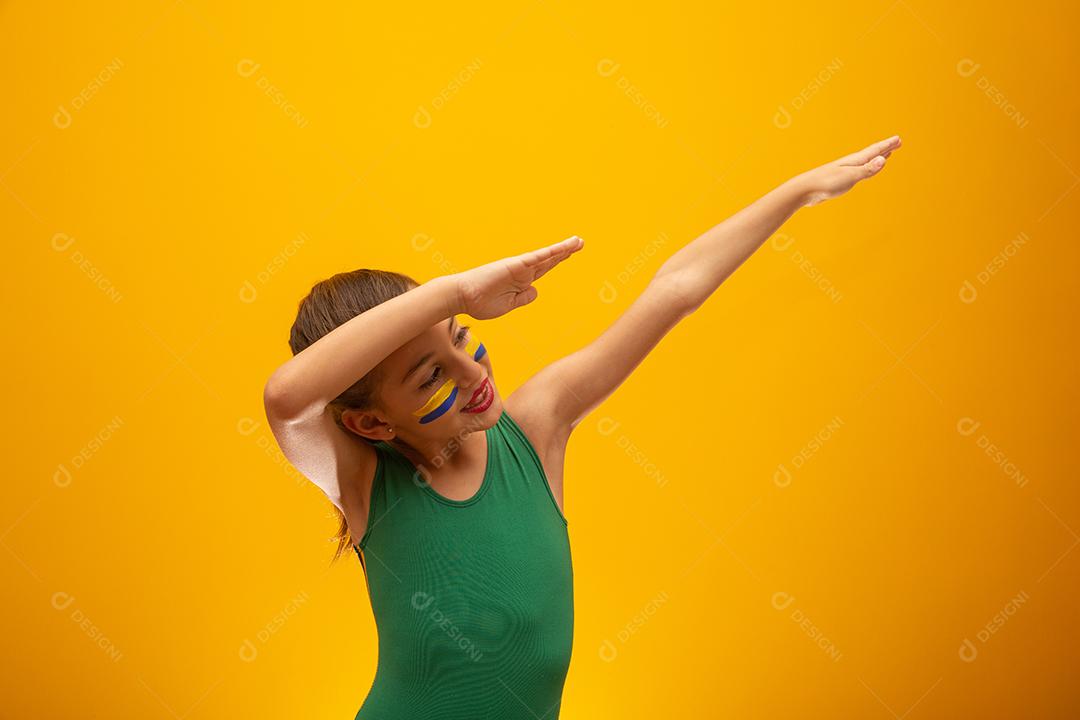 Torcedor de futebol, seleção brasileira. Copa do Mundo. Linda garotinha torcendo por seu time em fundo amarelo