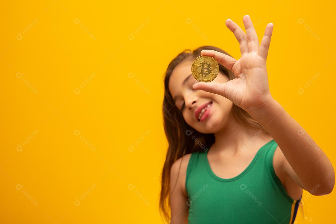 Criança segurando criptomoeda em metal. Moeda de ouro. Dourado. Em amarelo