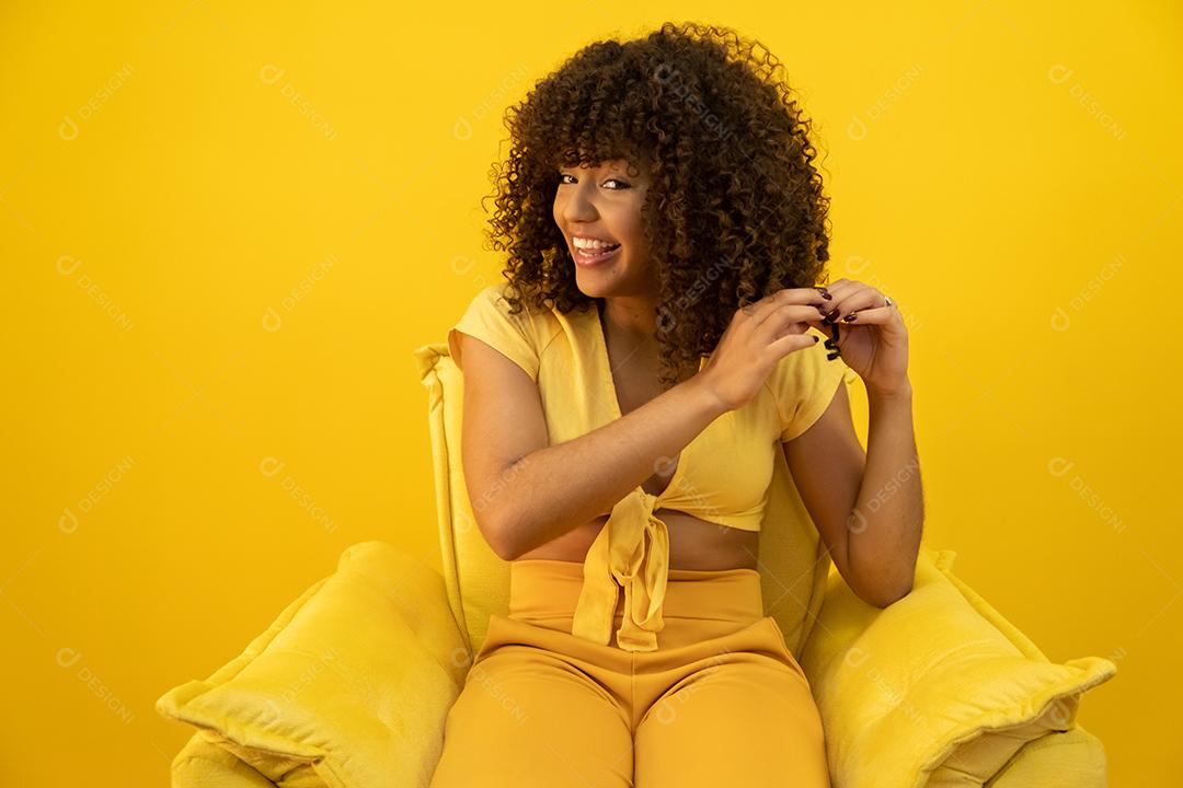 Feliz rindo mulher africana americana com seu cabelo encaracolado em fundo amarelo.