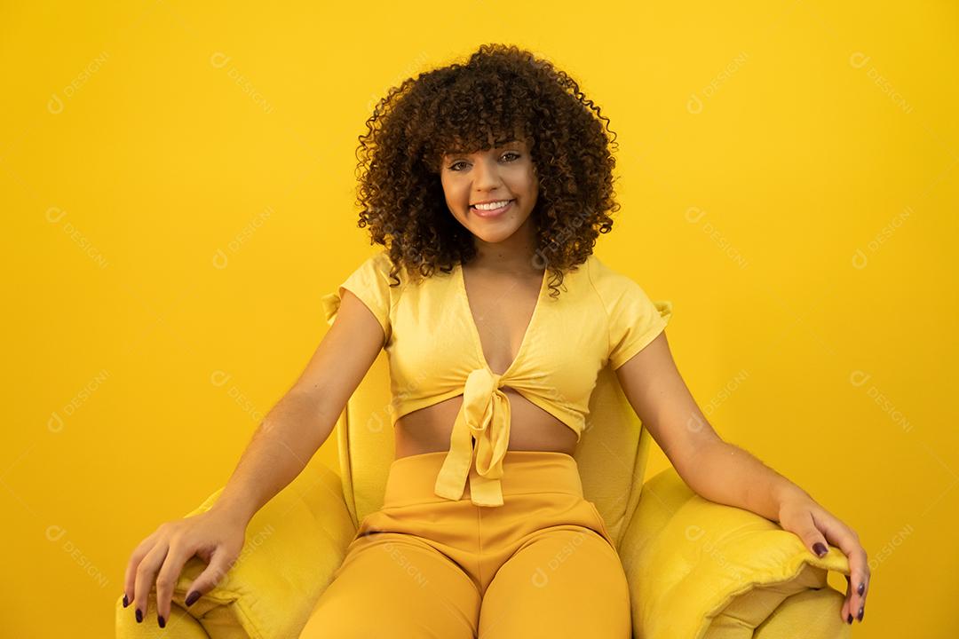 Feliz rindo mulher africana americana com seu cabelo encaracolado em fundo amarelo.