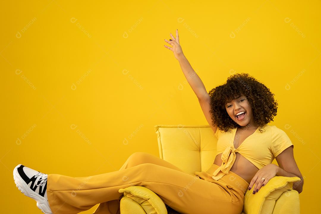 Feliz rindo mulher africana americana com seu cabelo encaracolado em fundo amarelo.