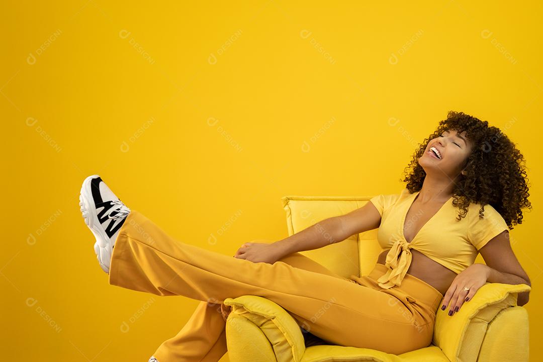 Feliz rindo mulher africana americana com seu cabelo encaracolado em fundo amarelo.
