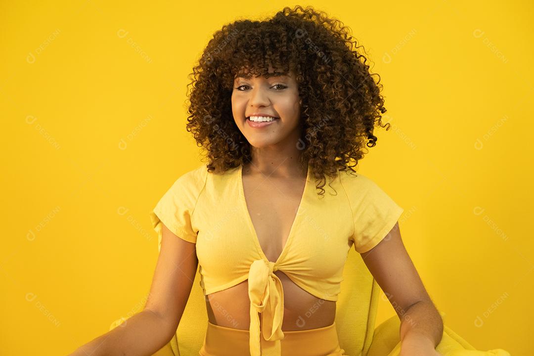 Feliz rindo mulher africana americana com seu cabelo encaracolado em fundo amarelo.