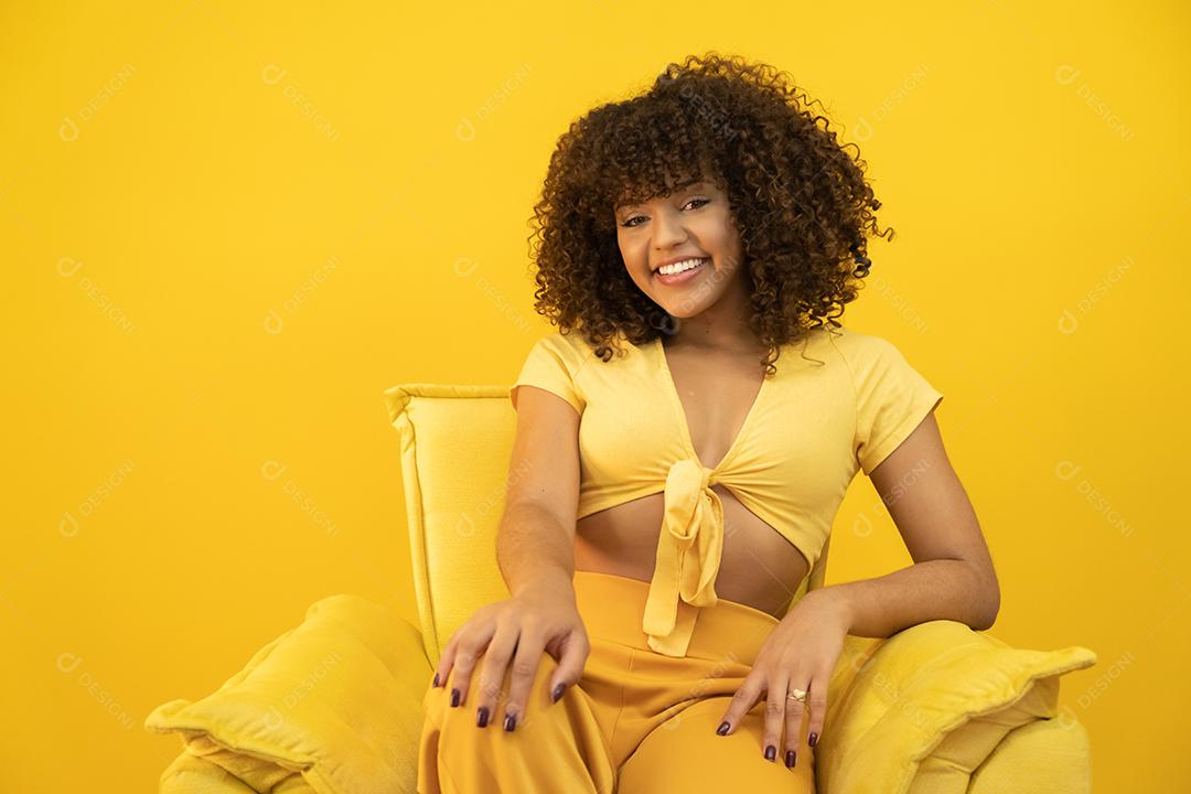 Feliz rindo mulher africana americana com seu cabelo encaracolado em fundo amarelo.