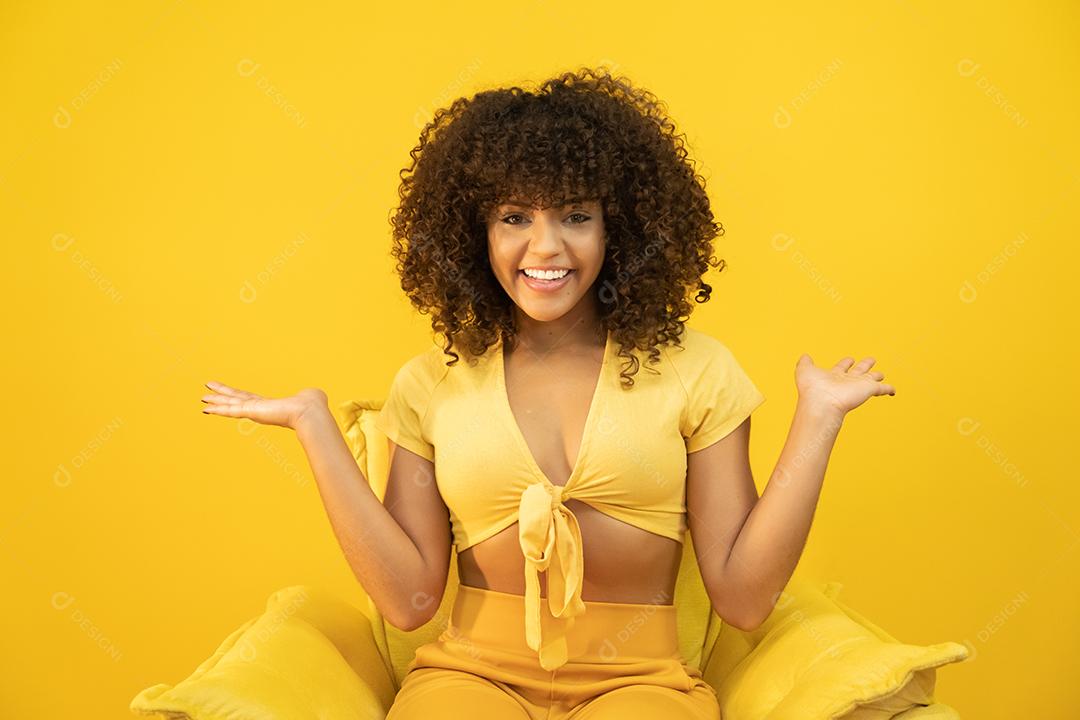 Feliz rindo mulher africana americana com seu cabelo encaracolado em fundo amarelo.