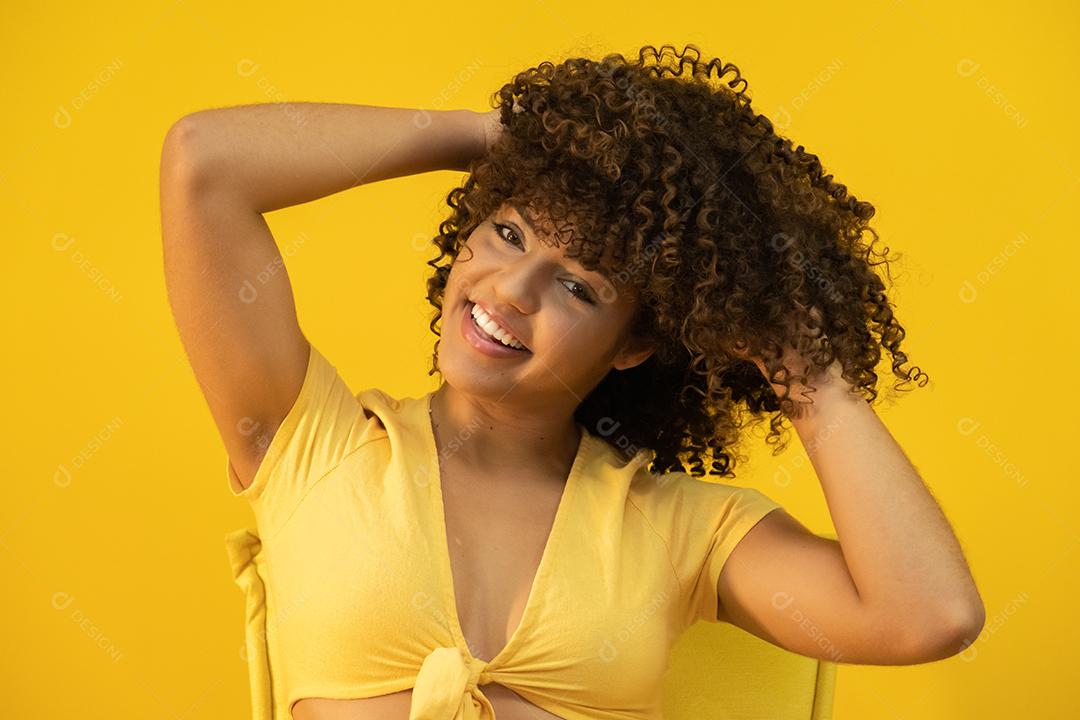 Feliz rindo mulher africana americana com seu cabelo encaracolado em fundo amarelo.